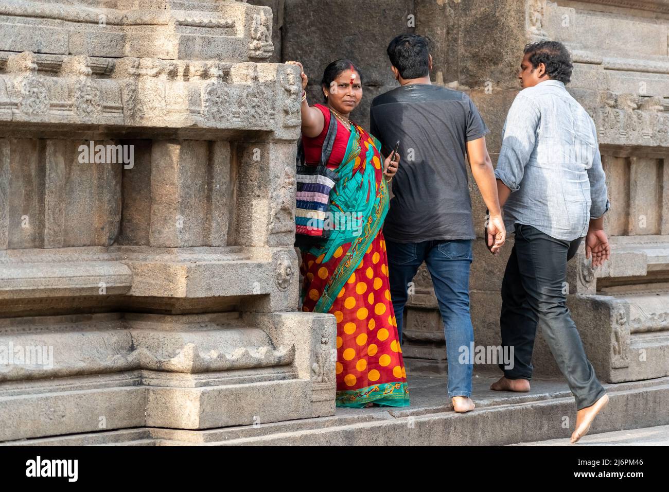 Vellore, Tamil Nadu, India - September 2018: An Indian woman wearing a red sari standing beside a wall at an ancient Hindu temple in the Vellore fort. Stock Photo