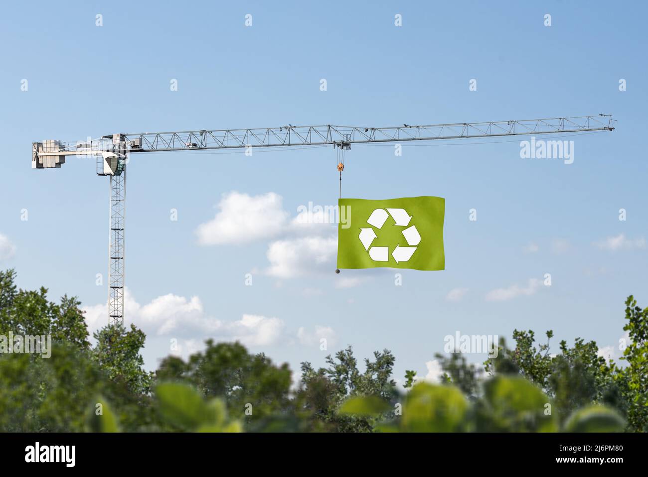 Building crane hoisting a green flag for sustainability Stock Photo