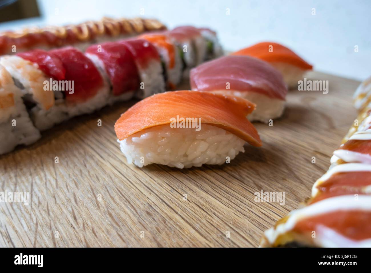 Angled, selective focus view of a variety of sushi rolls on a bamboo cutting board Stock Photo