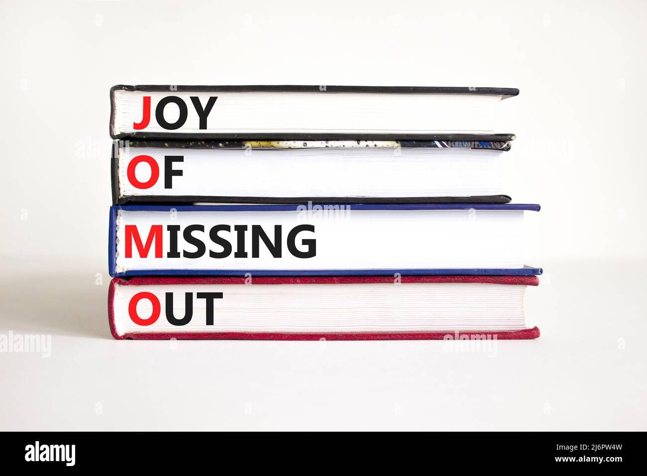 JOMO joy of missing out symbol. Concept words JOMO joy of missing out on books on a beautiful white table white background. Business JOMO joy of missi Stock Photo