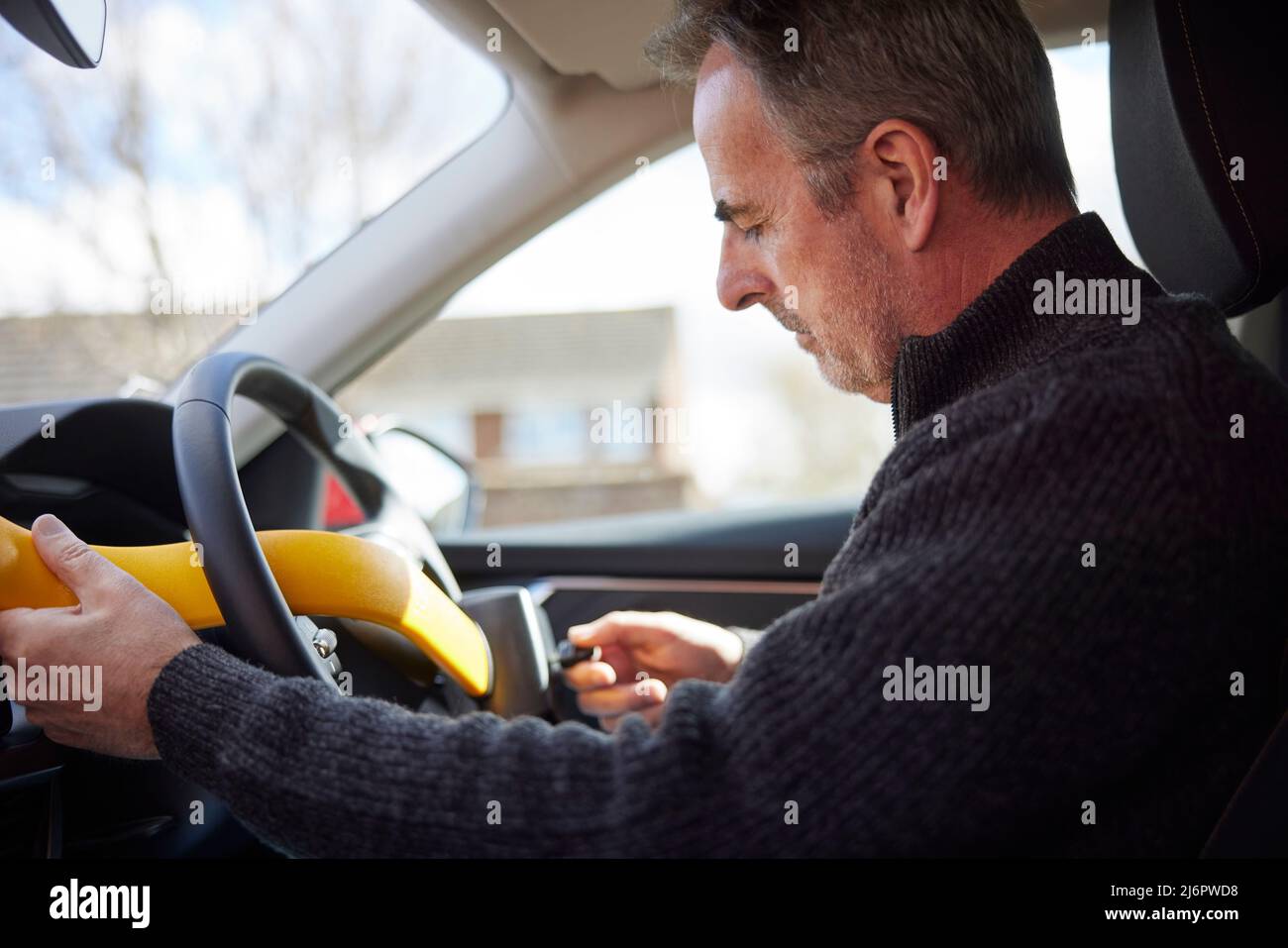 Mature Man Fitting Manual Steering Wheel Lock In Car Stock Photo