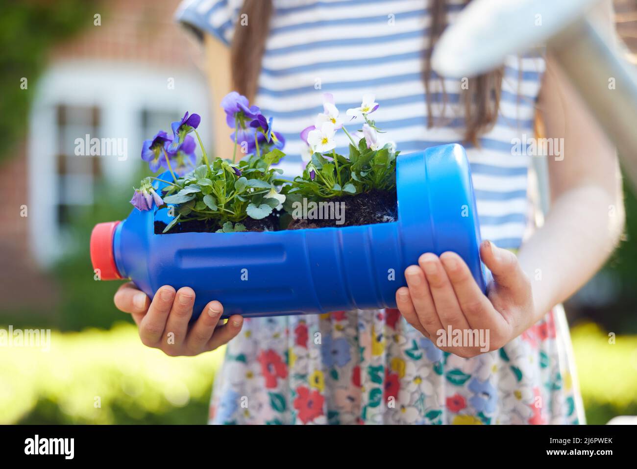 Close Up Of Girl Holding Recycled Plant Holder From Plastic Bottle Packaging Waste In Garden At Home Stock Photo