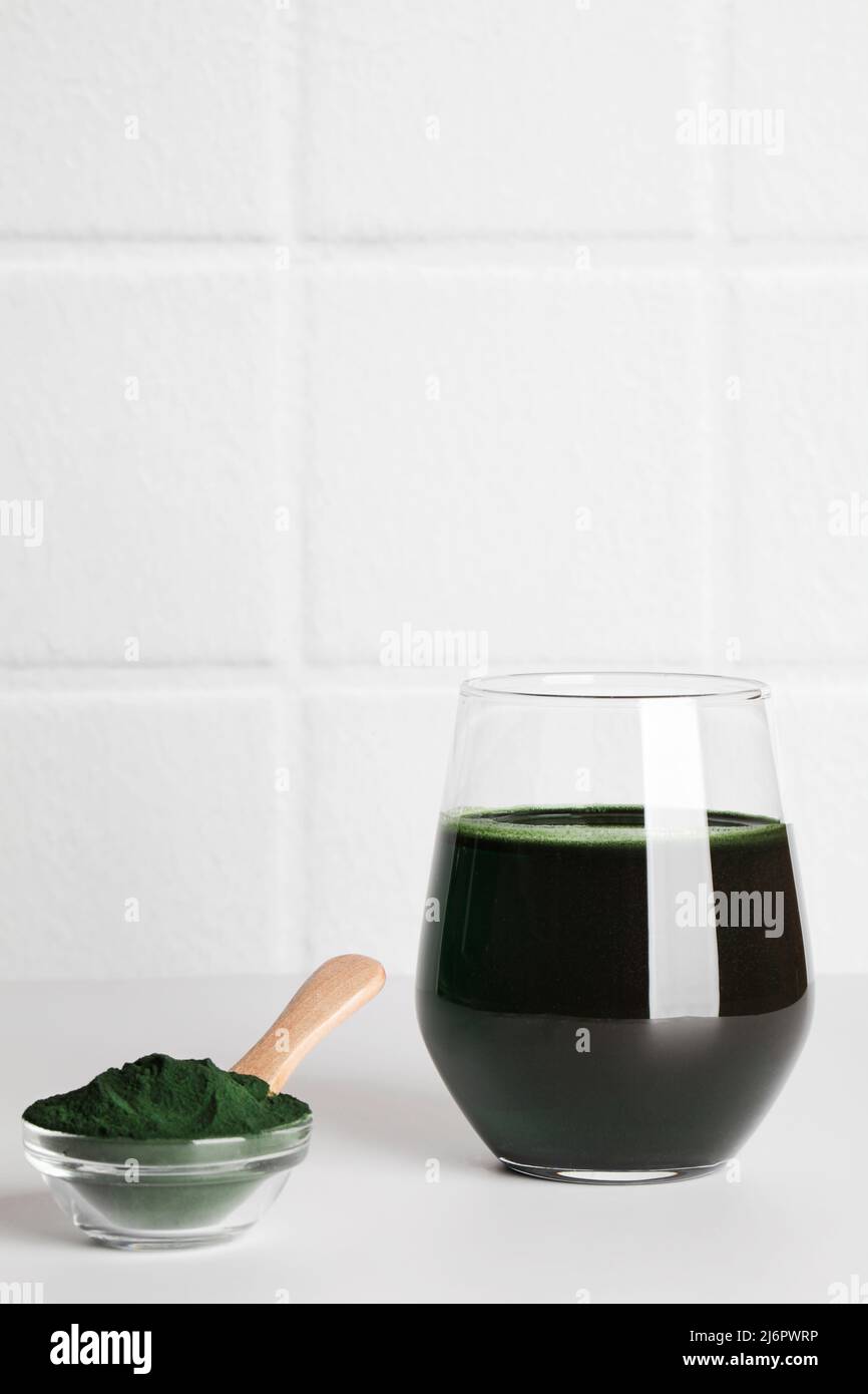 fresh green drink with spirulina in glass, spirulina powder with spoon