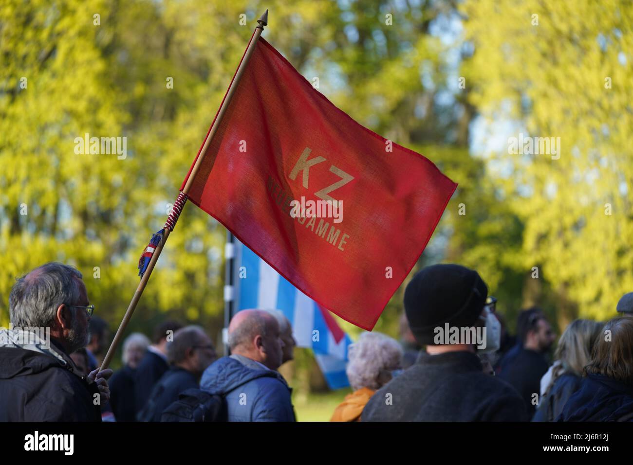 03 May 2022, Hamburg: A participant carries a red flag with the inscription 'KZ Neuengamme' at the memorial after the commemoration ceremony marking the 77th anniversary of the end of the war and the liberation of the prisoners at the Neuengamme Concentration Camp Memorial. Survivors as well as member associations of the Amicale Internationale KZ Neuengamme and other relatives of former Neuengamme Concentration Camp prisoners from Belgium, Denmark, Germany, France, Croatia, the Netherlands, Poland and Spain and Ukraine took part in the commemoration. Photo: Marcus Brandt/dpa Stock Photo