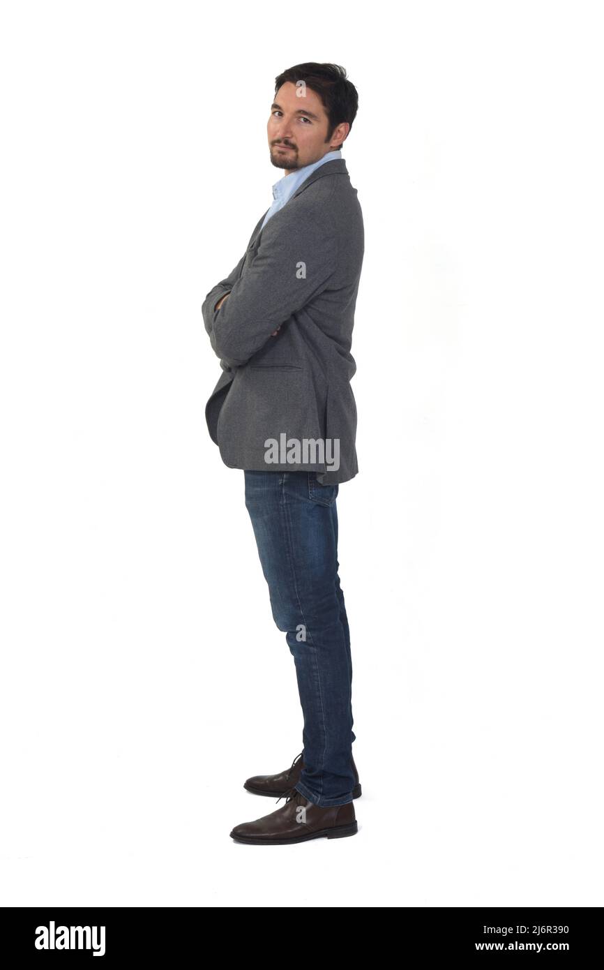 side view of a man with blazer and jeans, arms crossed looking at ...
