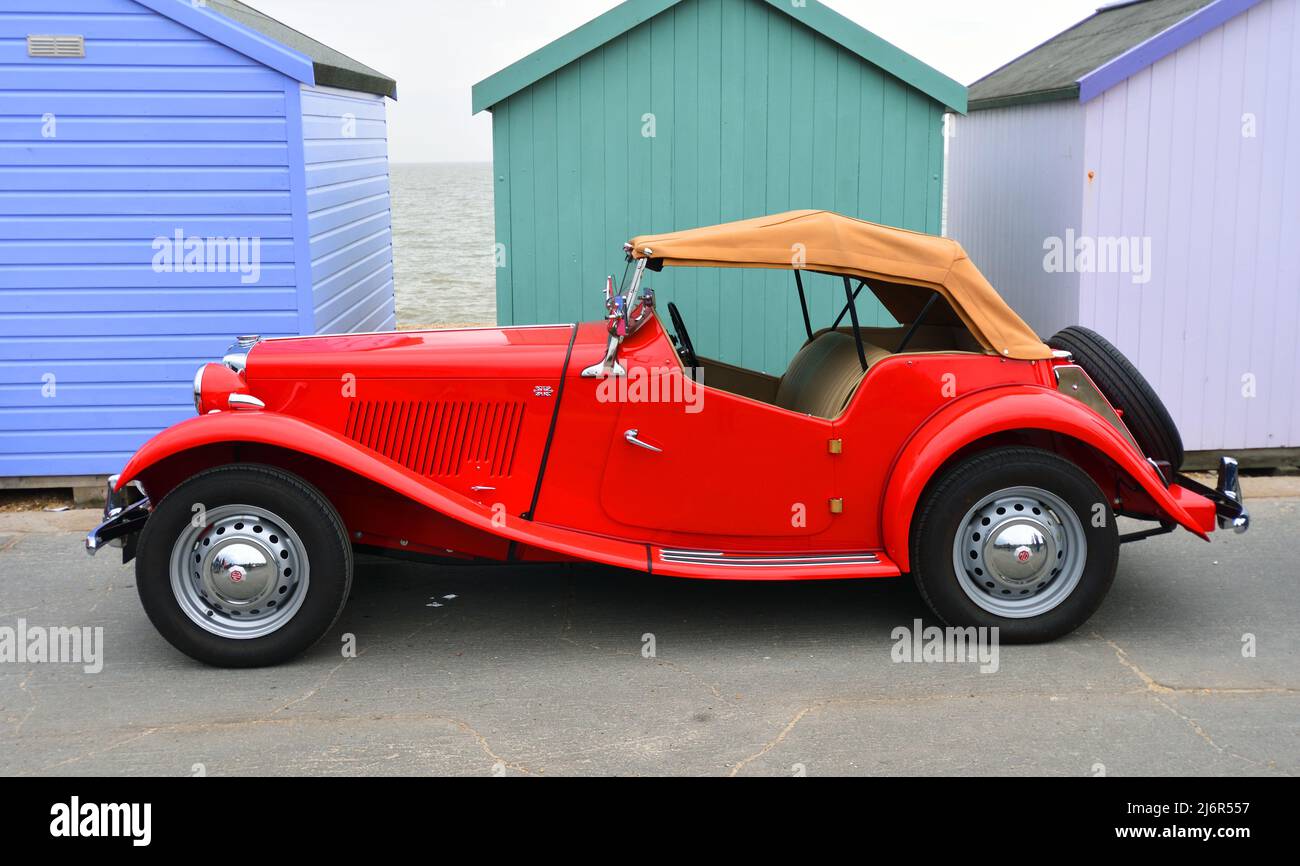 Classic Red MG Car Parked on seafront promenade in front of beach huts. Stock Photo