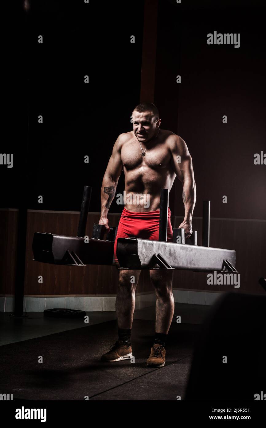 Very power athletic guy, execute exercise in sport hall. Closeup of a muscular young man lifting