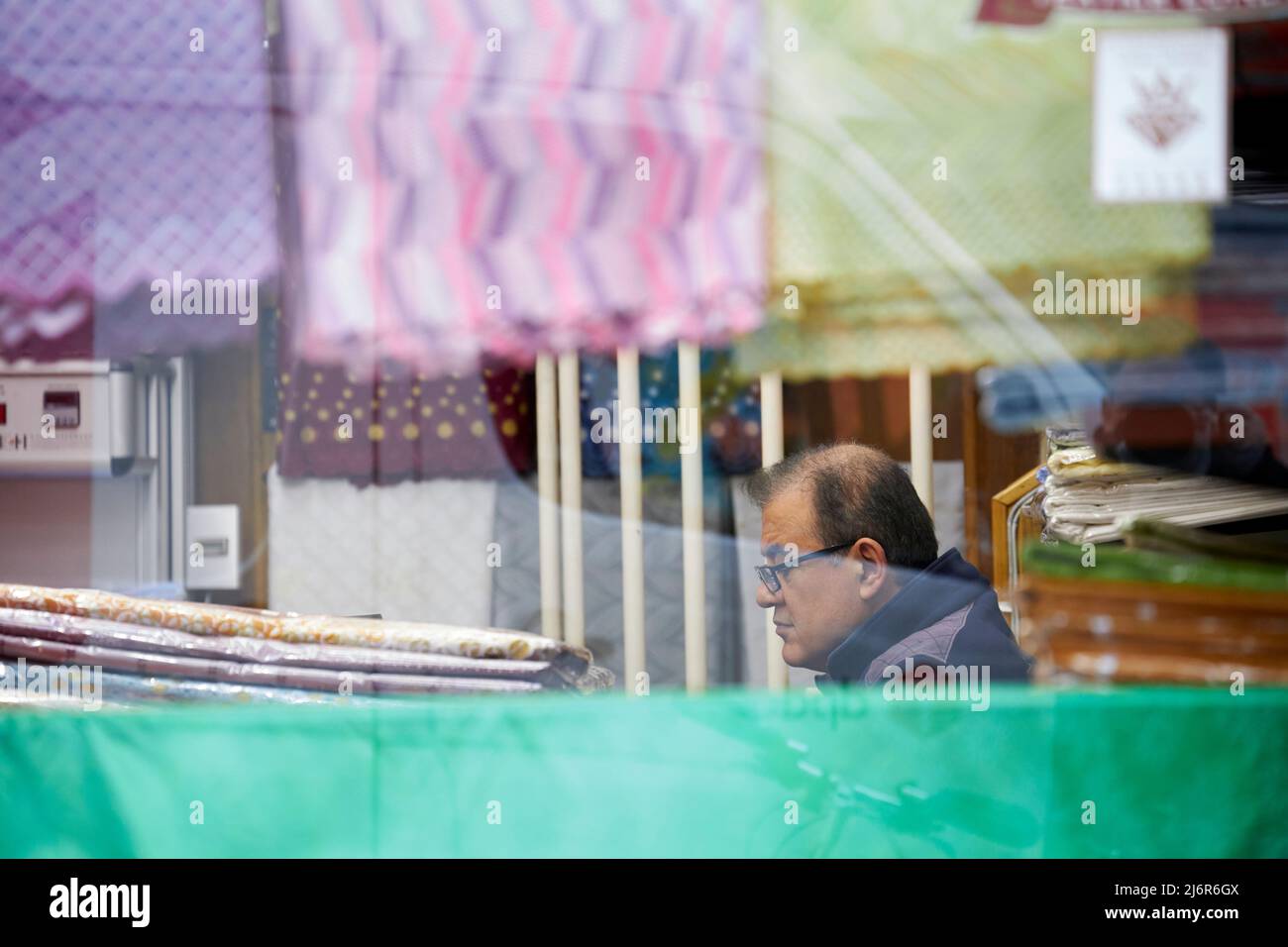 Man in shop with materials in Petticoat Lane. Stock Photo