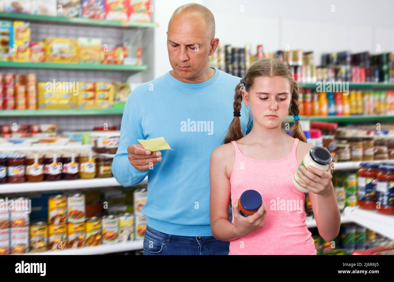 interested father doing shopping with preteen girl in supermarket Stock Photo