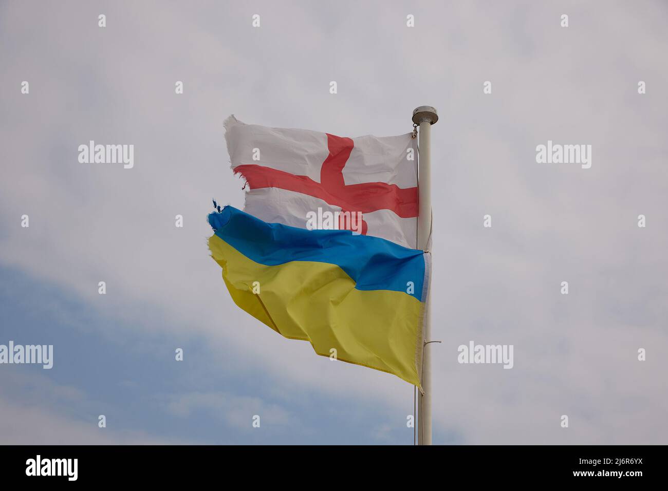English and Ukrainian flags seen together outdoors on one flag pole Stock Photo