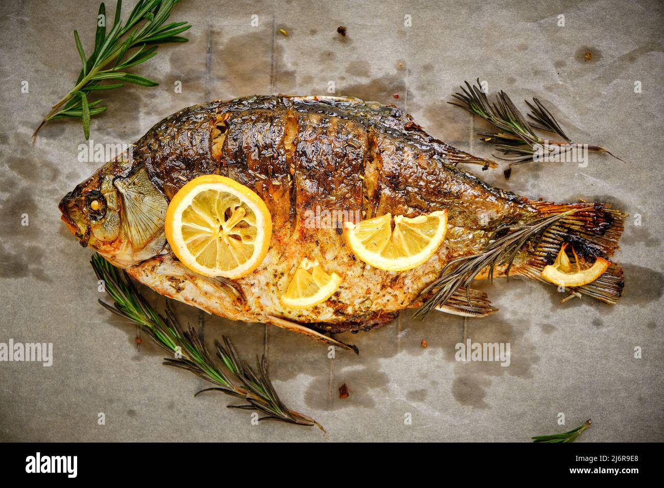 Cooked on parchment paper, baked fish with spices, lemon and rosemary