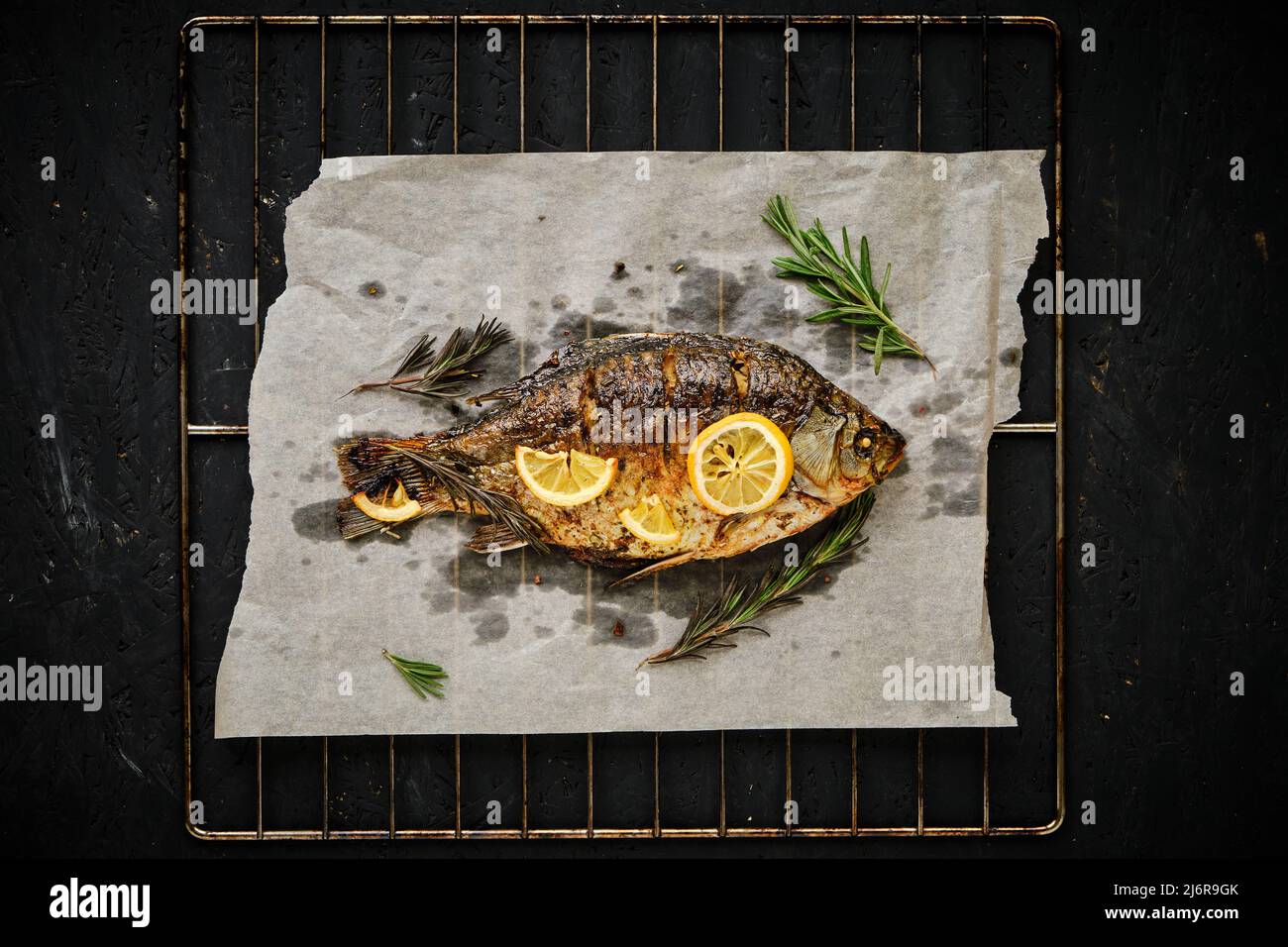 Baked fish cooked on parchment paper with spices, lemon and rosemary