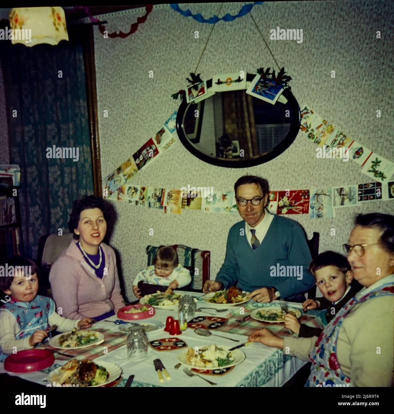 An extended family Christmas in 1962. Grandparents, a young mother and 3 children sit around the dinner table. Stock Photo