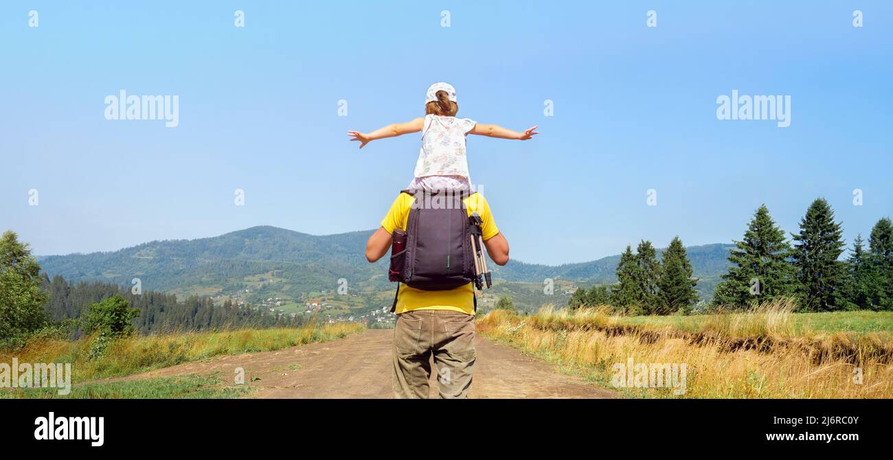 Piggyback ride father child travel mountain kids freedom child on shoulders dad and daughter father walking hiking trip nature kid arms spread out Stock Photo
