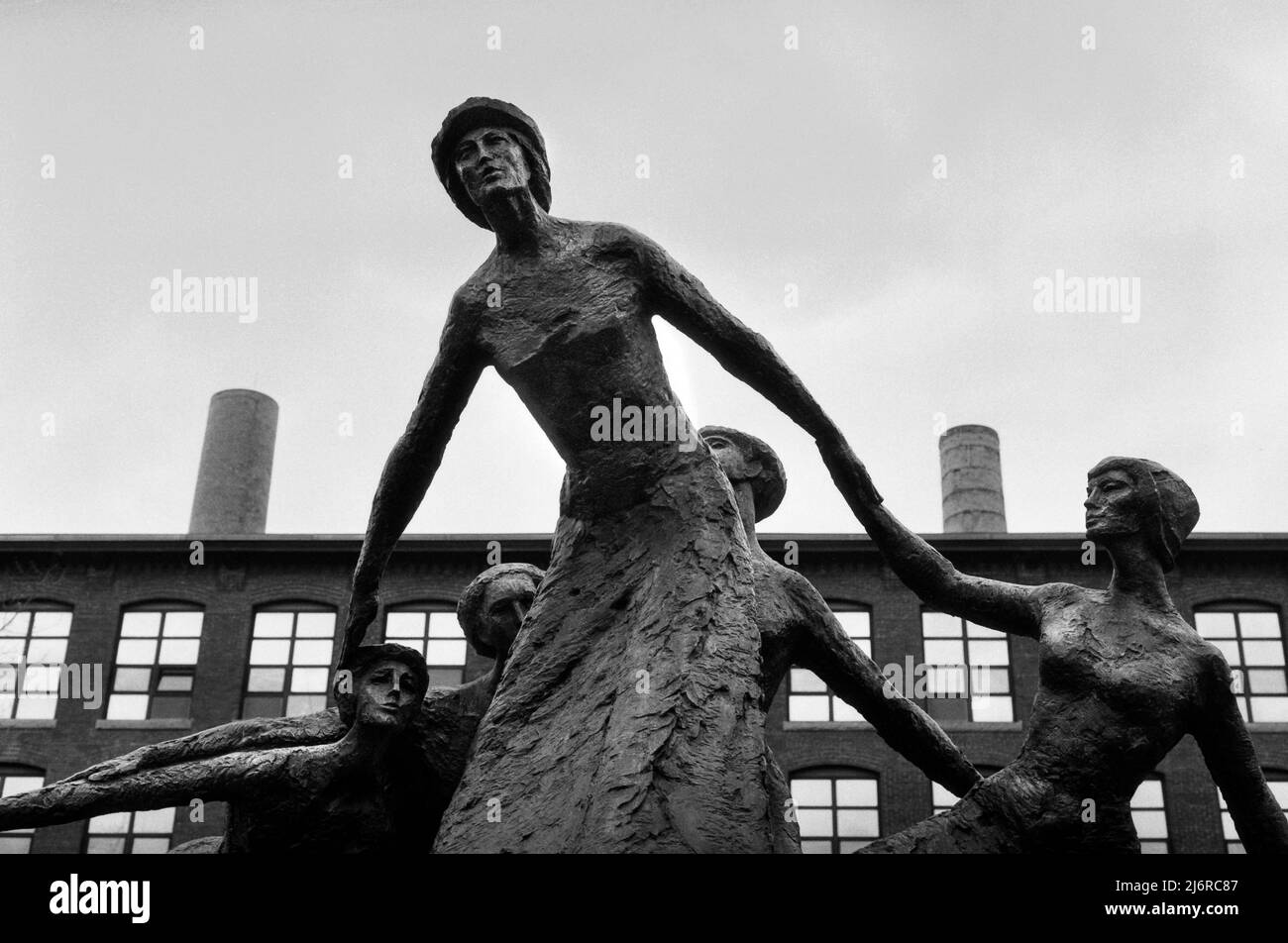 A dramatic sculpture by Mico Kaufman (1989) of 19th-century mill workers rising above their struggles with vintage textile mills in the background. Ma Stock Photo