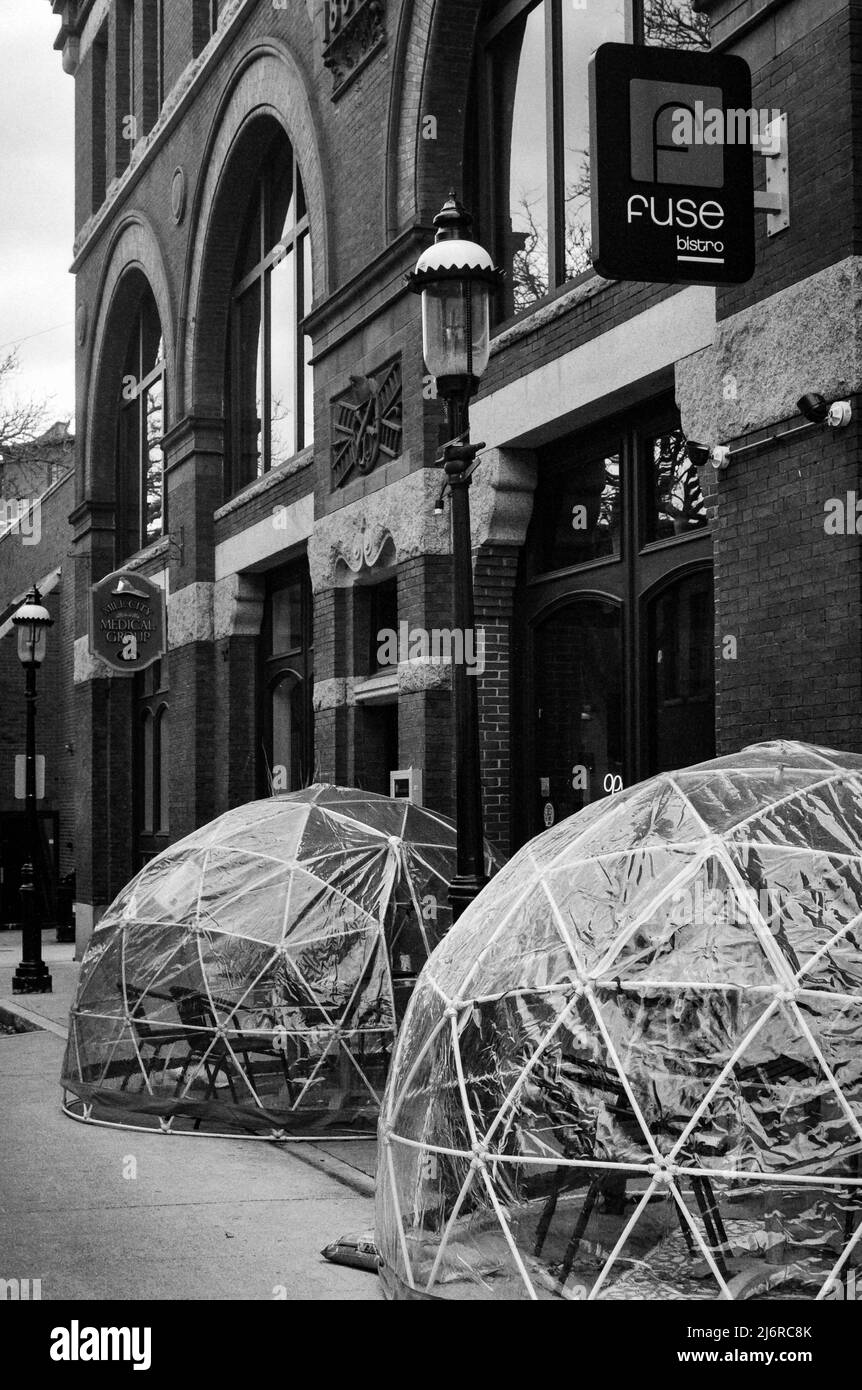 Two heated clear plastic Igloos sit as relics from the COVID pandemic in front of a repurposed firehouse which is now a restaurant in Lowell, Massachu Stock Photo