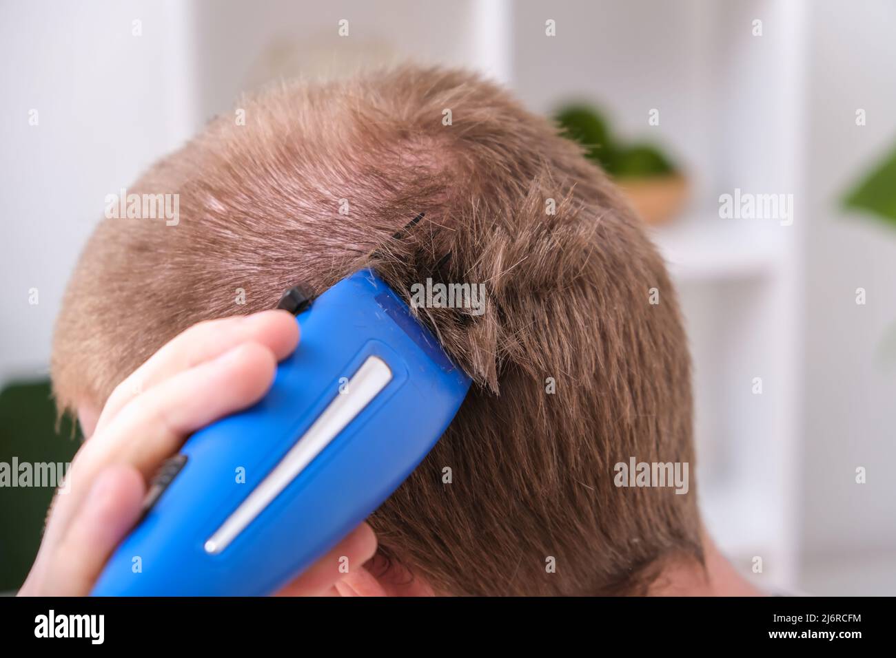 A man cuts his hair with a clipper. Cutting a short hairstyle at home