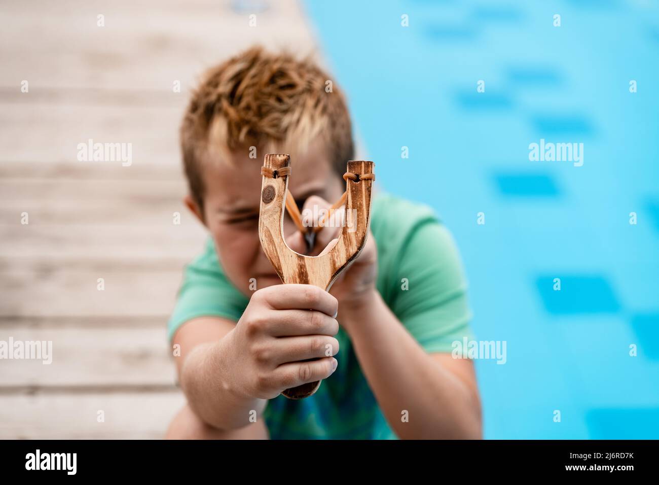 A boy shoots a slingshot near the pool Stock Photo Alamy
