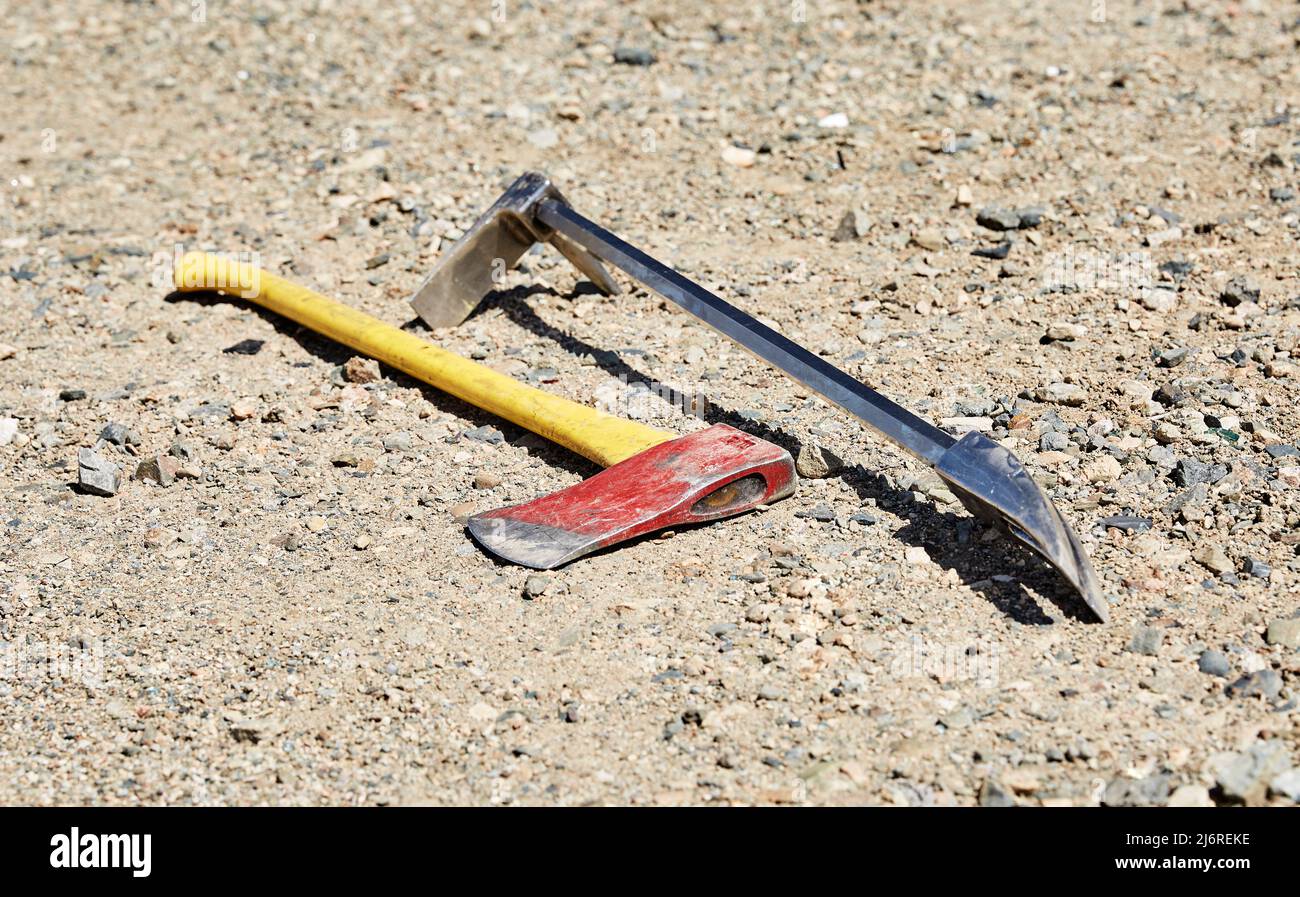 Fireman's forceable entry tools, a halligan and an axe laying on the ground Stock Photo