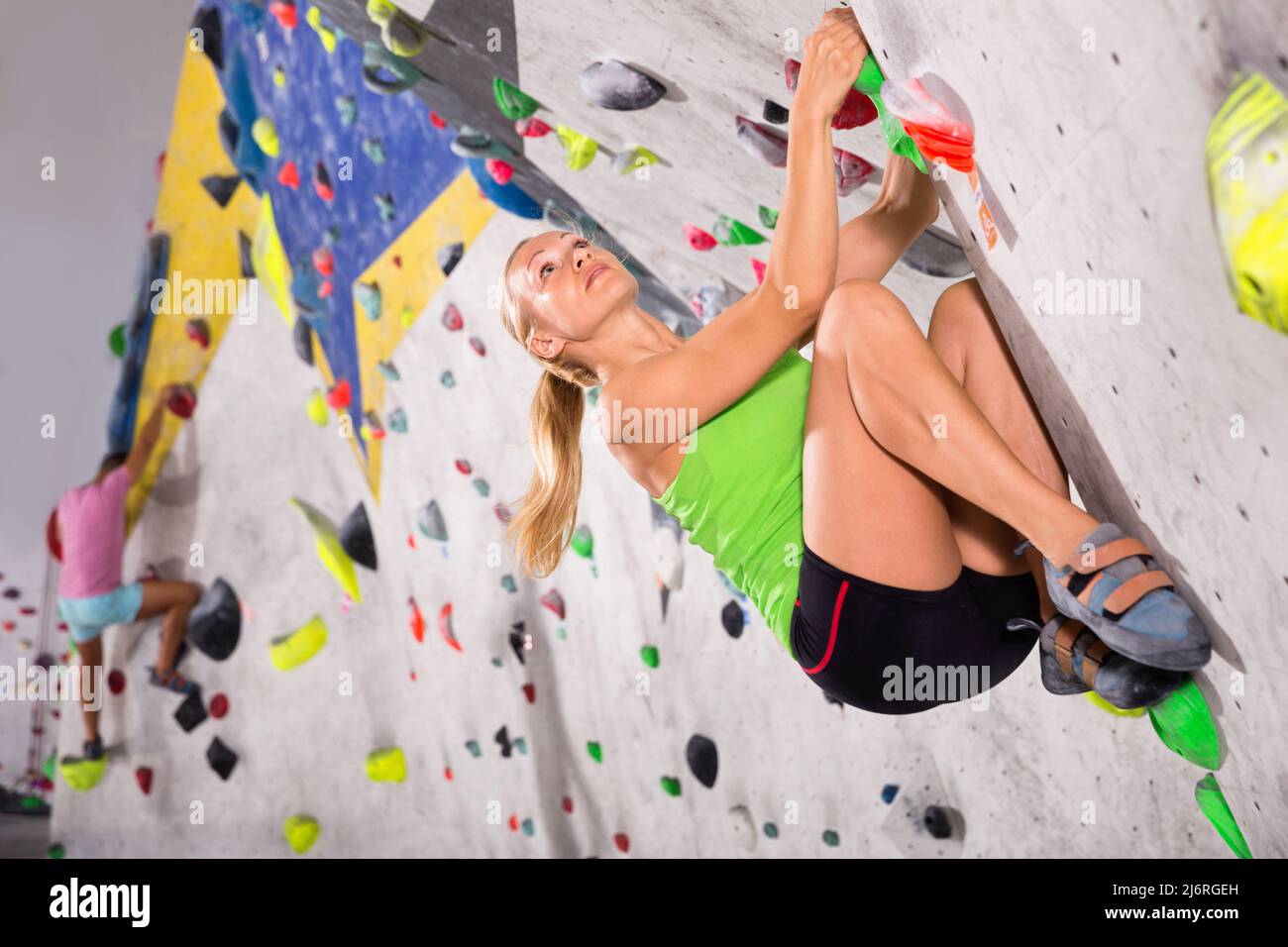 Young sporty woman training at bouldering gym without special climbing ...