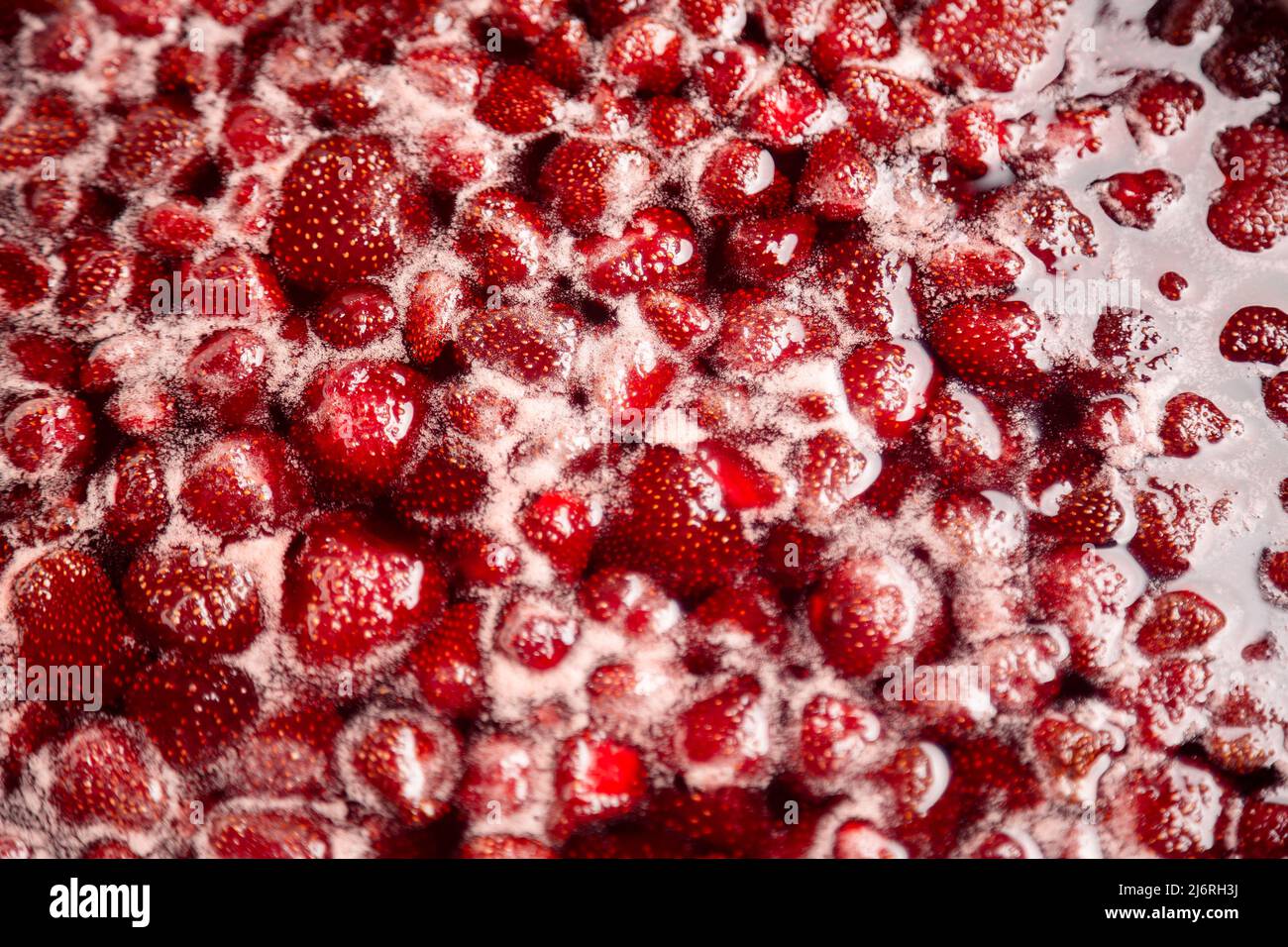 Process of making homemade raspberry jam. Red sweet syrup boiling on the stove closeup. Strawberry jam looks very appetizing. Boiling homemade strawberry jam. Make a strawberry jam. Stock Photo