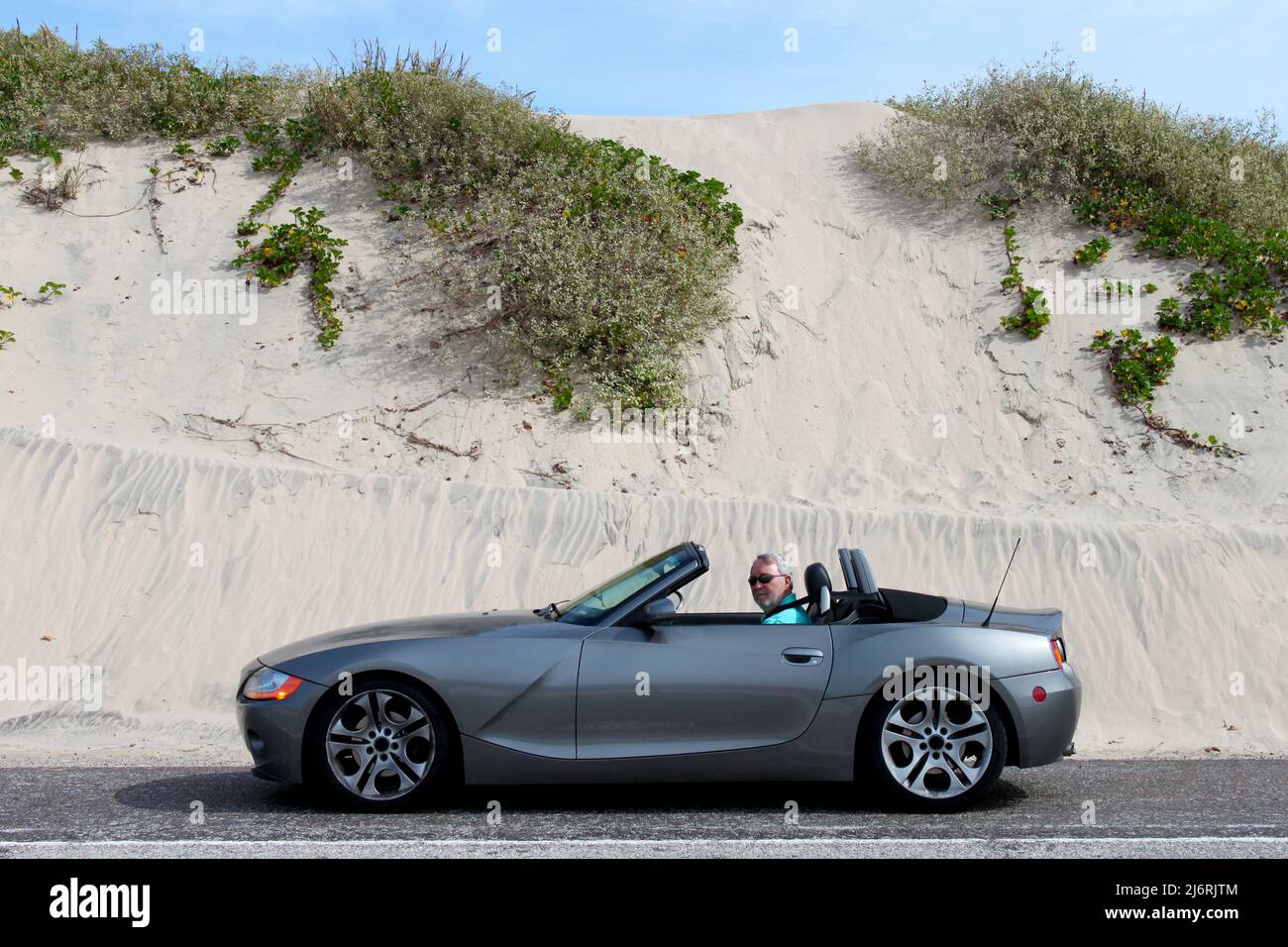 Grey Haired Man in Convertible by Sand Dunes Stock Photo