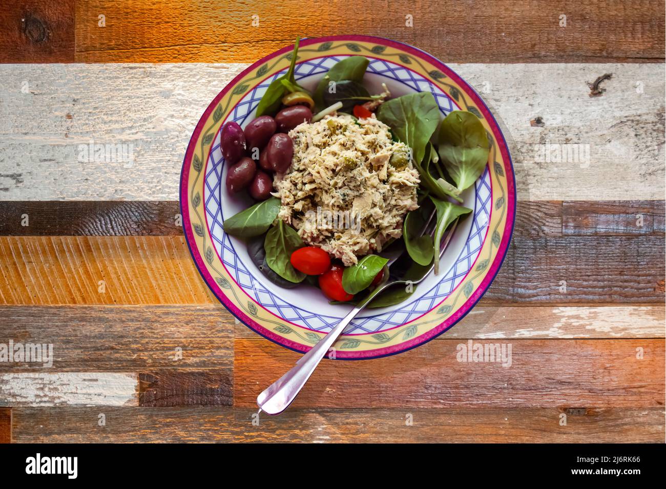 Homemade chicken salad served in a pretty bowl with spinach kalamata olives and cherry tomatoes - on rough wood table Stock Photo