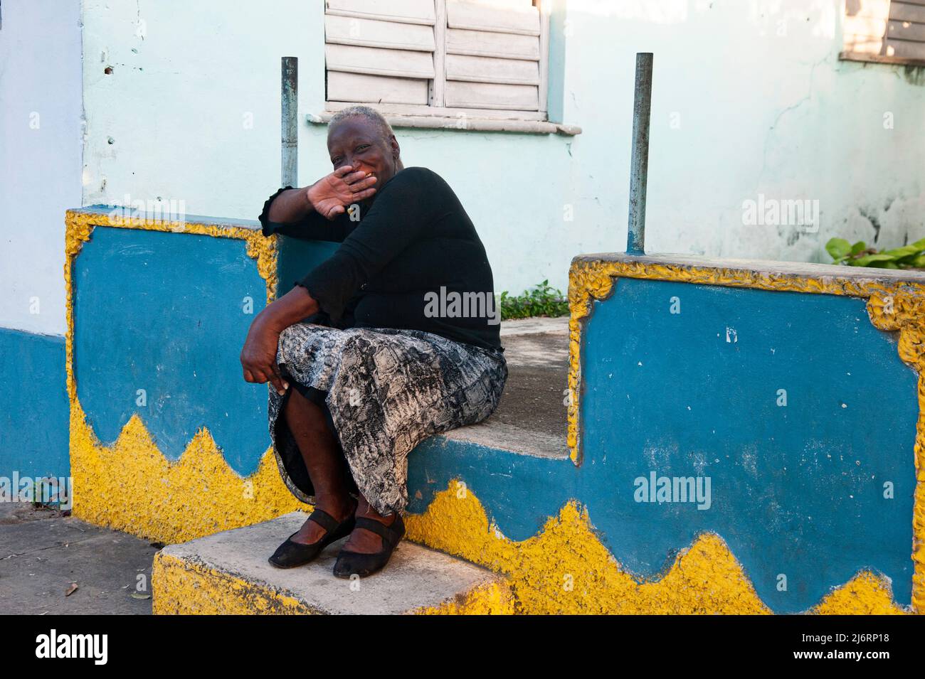 Cuban woman tries to hide her face while waving at the camera  in Havana, Cuba. Stock Photo
