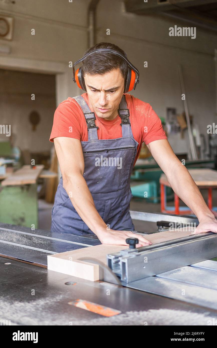 Woodworker cutting plank with table saw in workshop Stock Photo