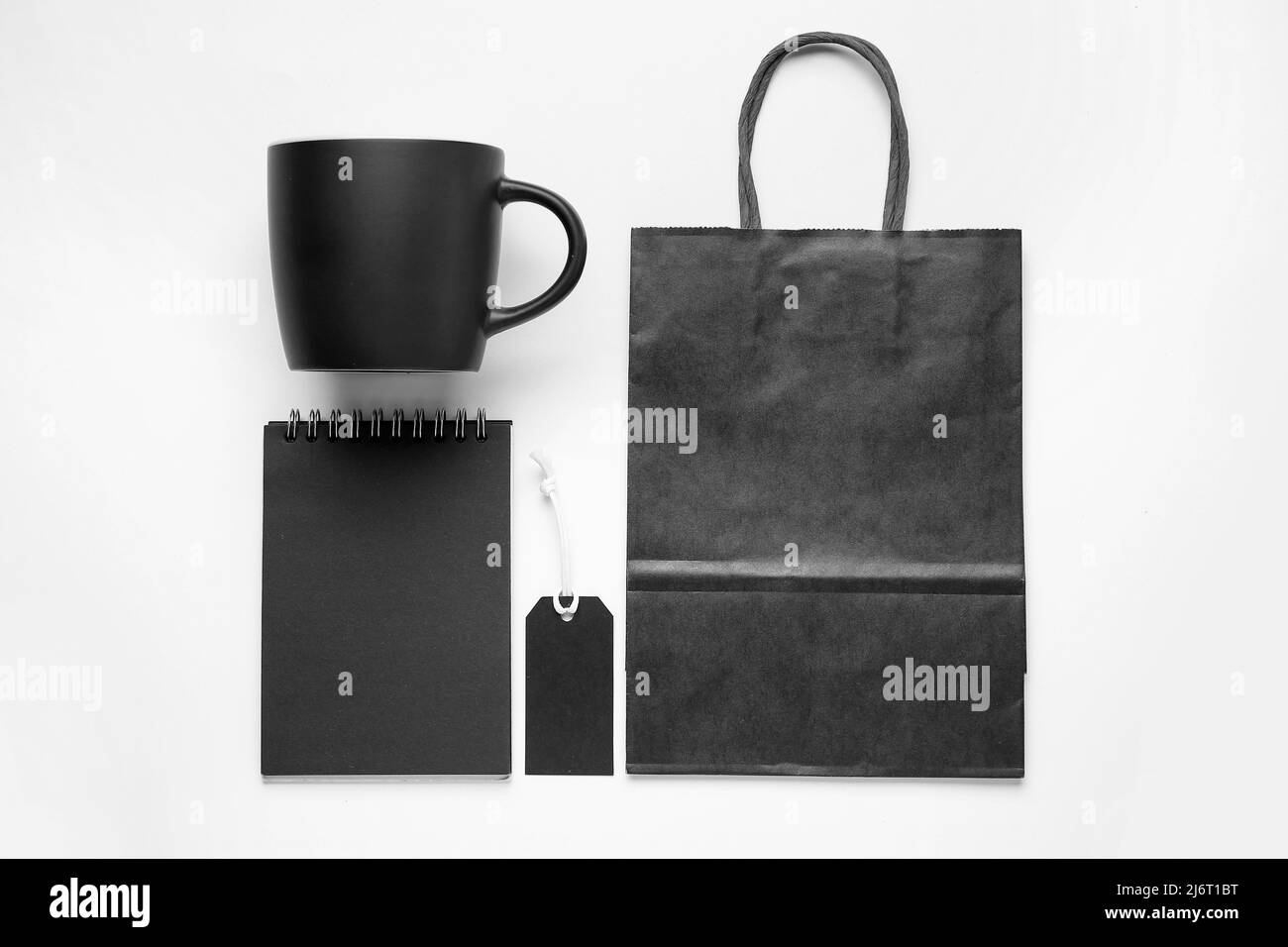 Blank cup, paper bag, notebook and tag on white background Stock Photo