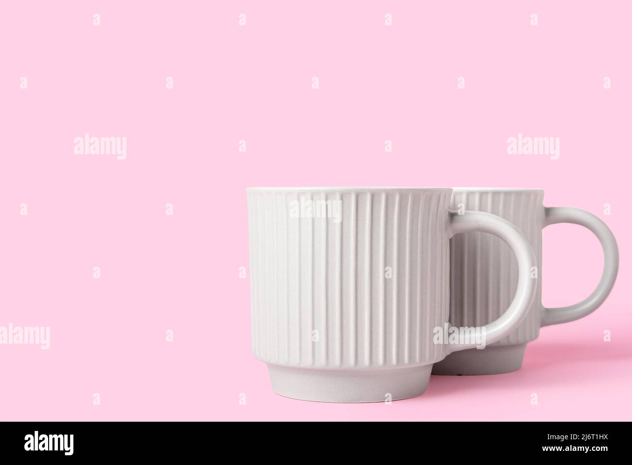 Two ceramic cups on pink background Stock Photo