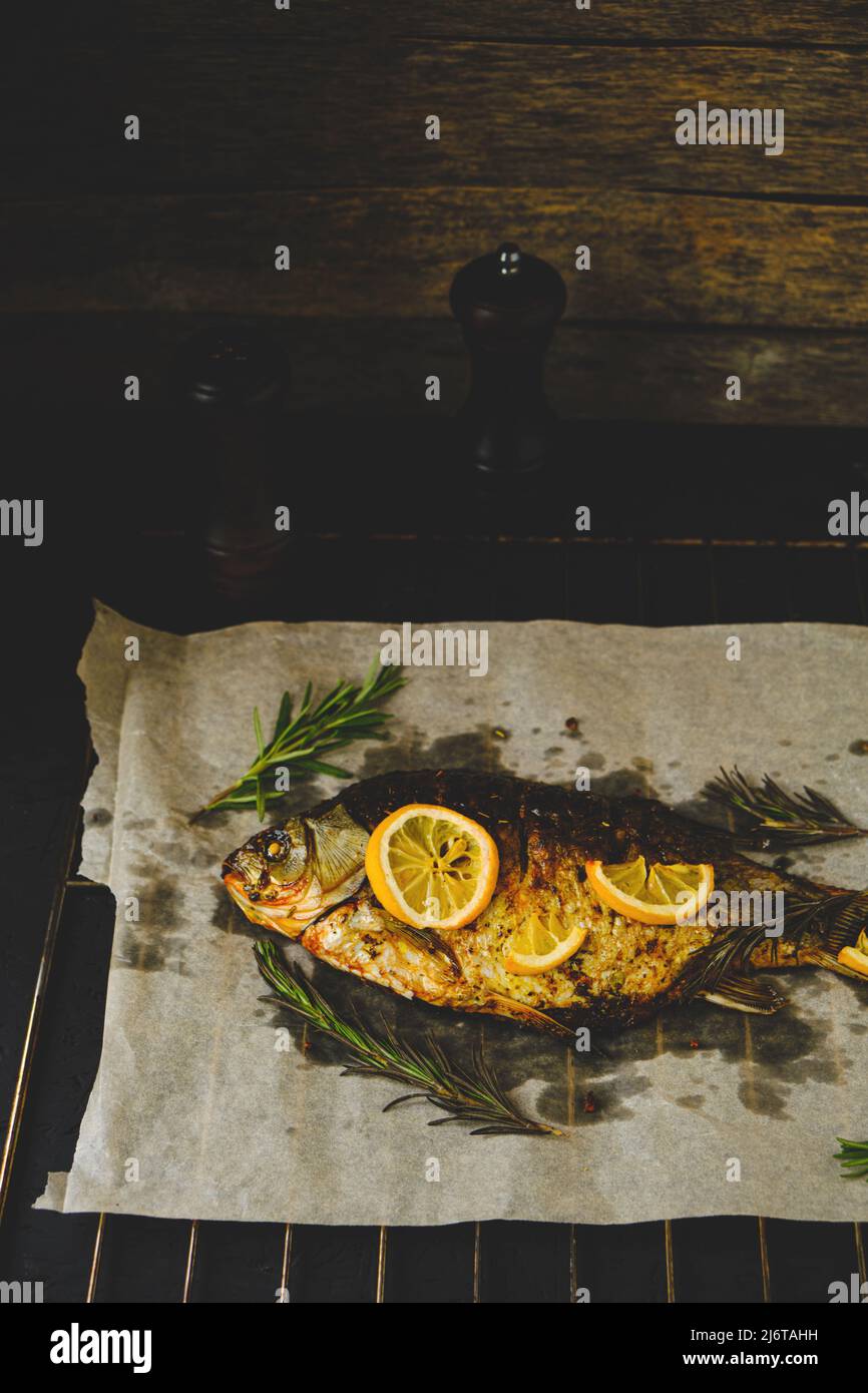 Baked fish with herbs and lemon is laid out on parchment paper, with ...
