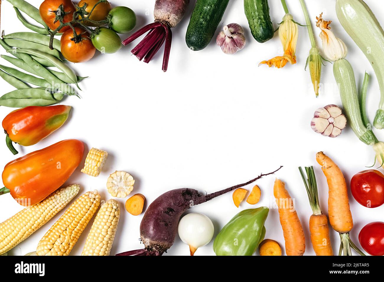 Creative layout made of autumn vegetables. Tomatoes, onion, cucumber, carrot, garlic, red beet, pepper, zucchini, maize and green haricot on white stu Stock Photo