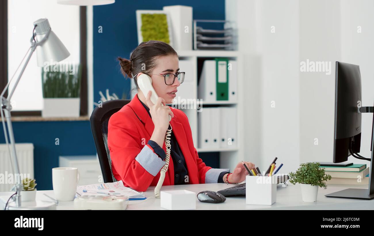 Company secretary having remote conversation on landline phone, working on financial development
