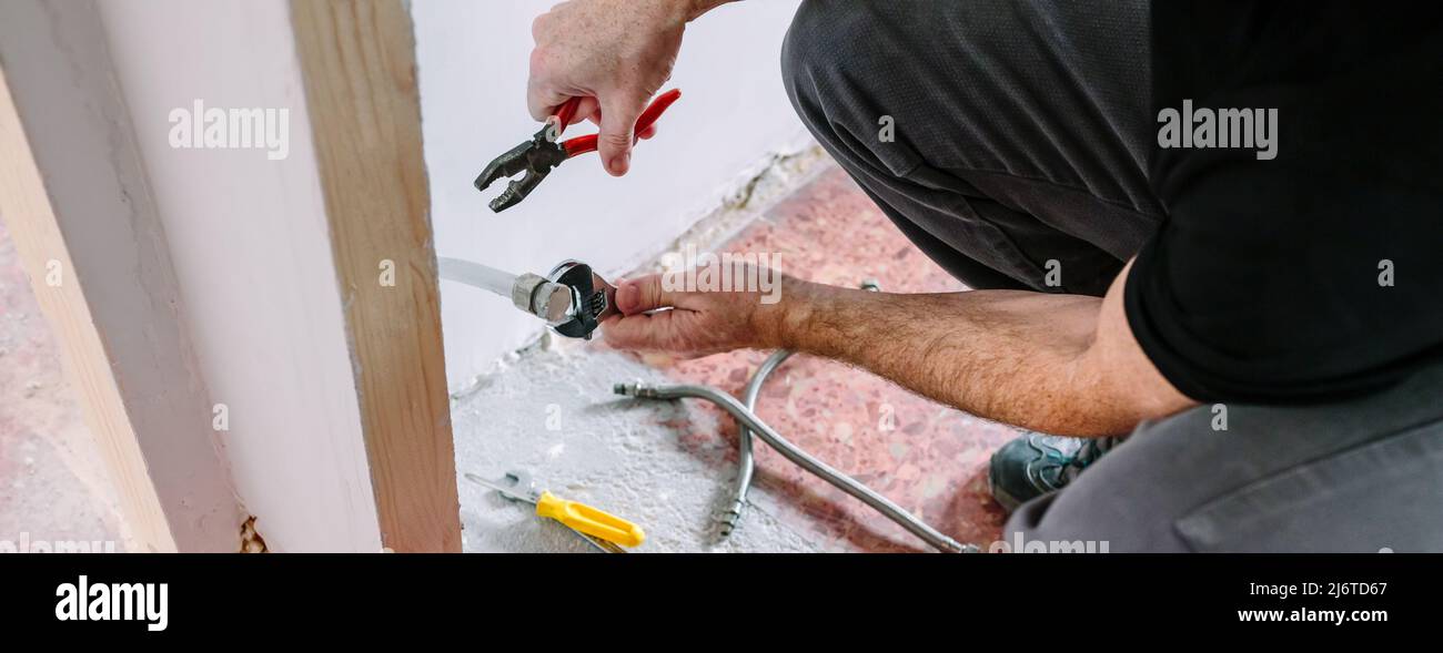 Plumber doing heating installation on a construction site Stock Photo