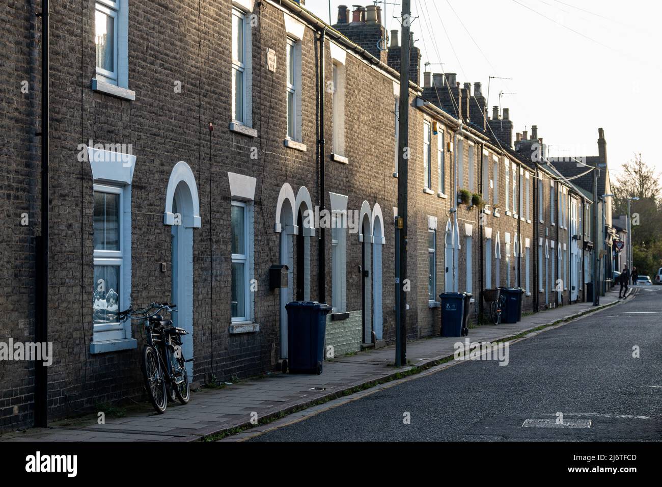 A view of Victorian yellow brick terraced houses with bins and a bicycle outside,  Kingston Street, Cambridge, UK Stock Photo