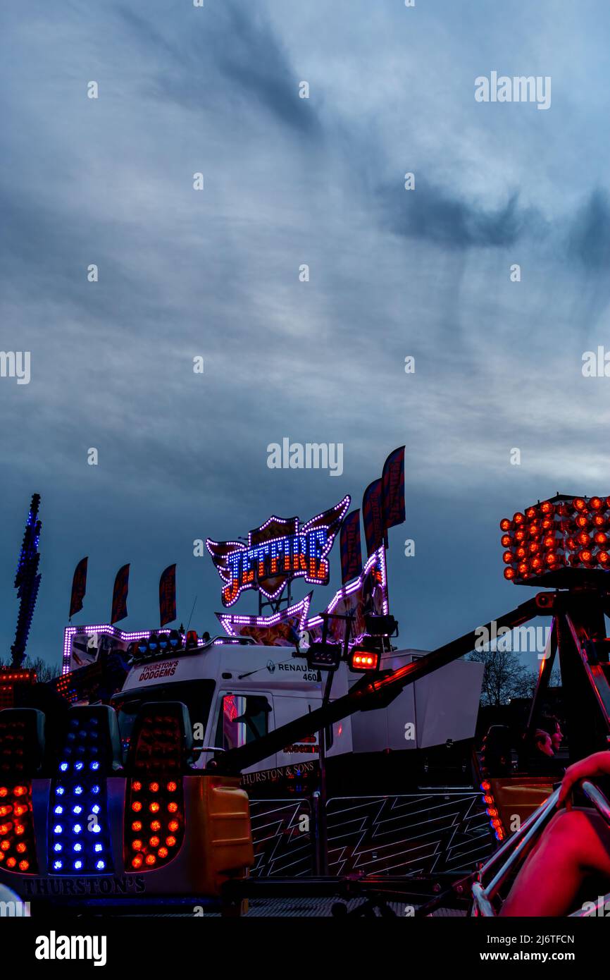 The blue and red lights of the Jetfire funfair ride brighten the night sky. Stock Photo
