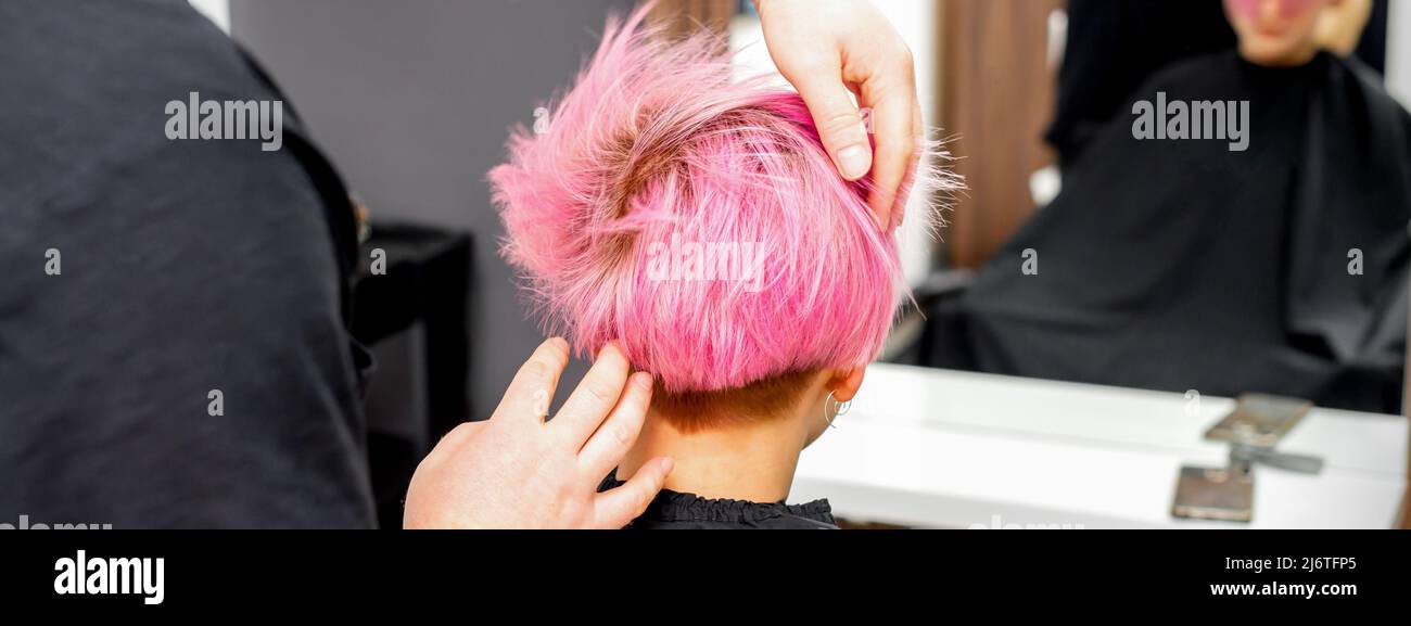 Hairdresser with hands is checking out and fixing the short pink