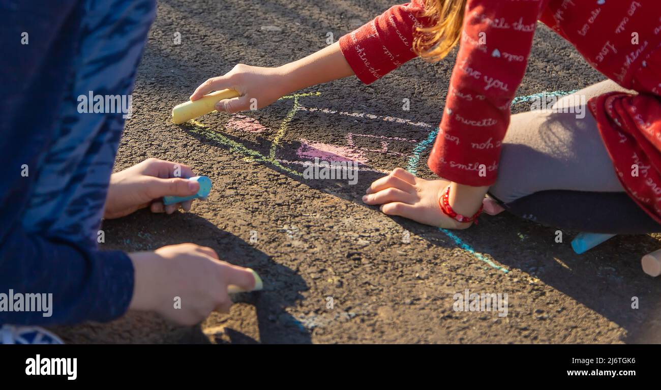 Children draw a house with chalk on the pavement. Selective focus. Kids ...