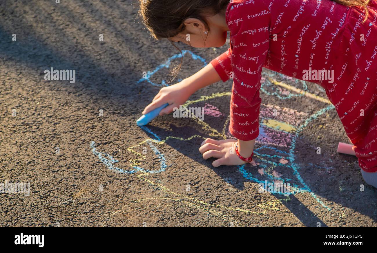 Children draw a house with chalk on the pavement. Selective focus. Kids ...