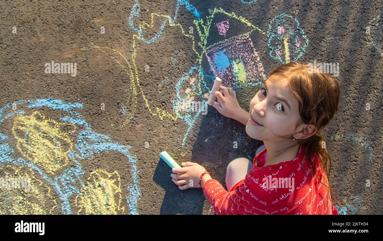 Children draw a house with chalk on the pavement. Selective focus. Kids ...