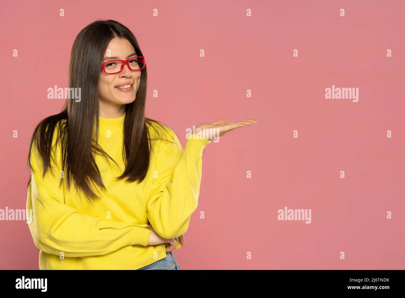 Young woman over isolated pink background presenting an idea or product while smiling Stock Photo