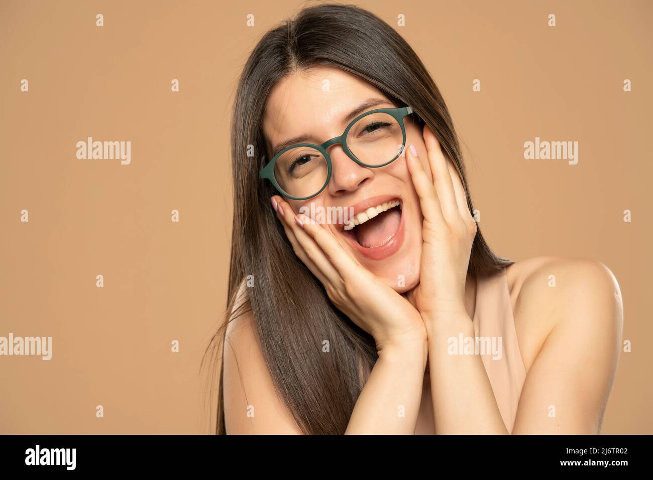 Happy excited beautiful woman with eyeglasses on a beige background Stock Photo