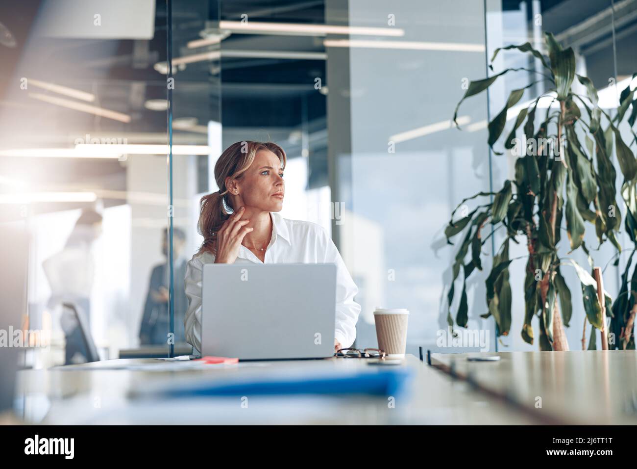 Focused businesswoman working on laptop and looking out the window at