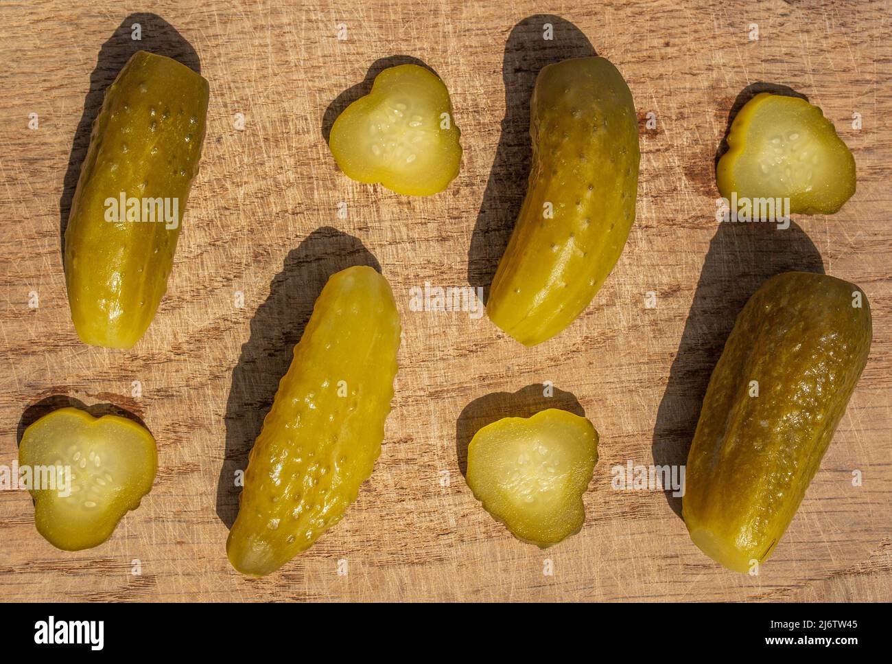 Salted pickled cucumbers cut and whole on wooden texture Stock Photo