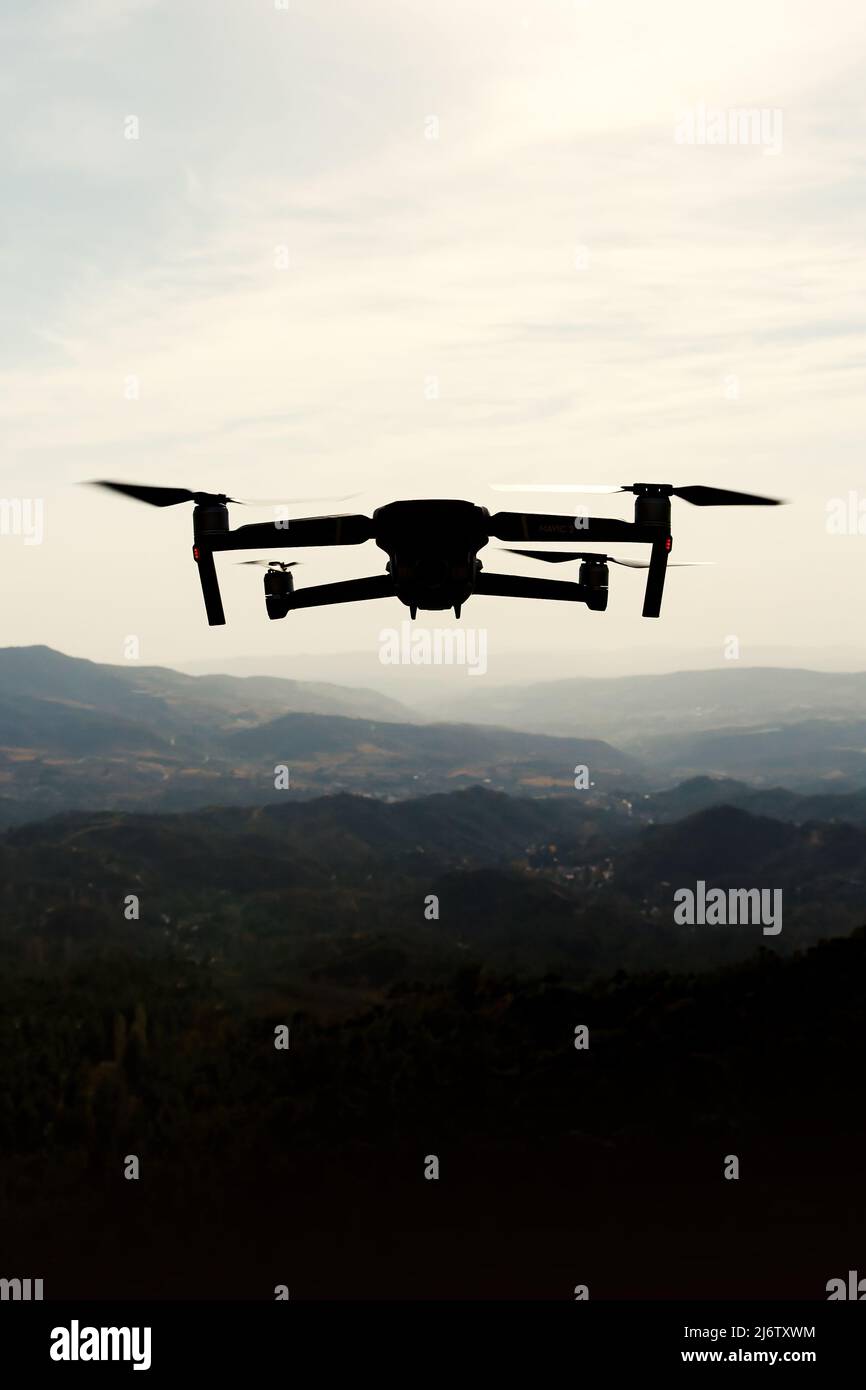 Folding small drone is flying over the mountains. Stock Photo