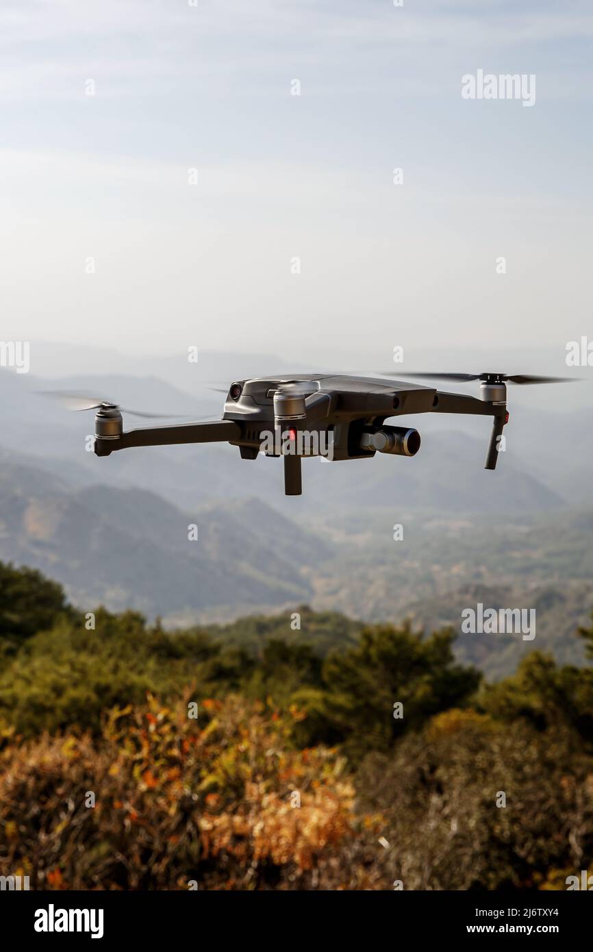 Folding small drone is flying over the mountains. Stock Photo