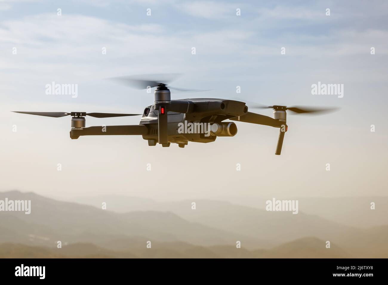 Folding small drone is flying over the mountains. Stock Photo
