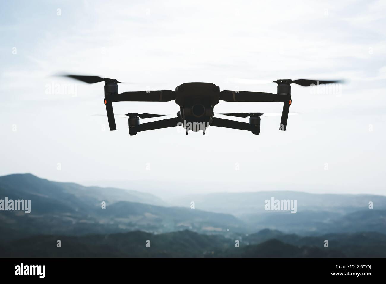 Folding small drone is flying over the mountains. Stock Photo