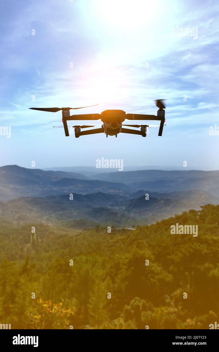 Folding small drone is flying over the mountains. Stock Photo